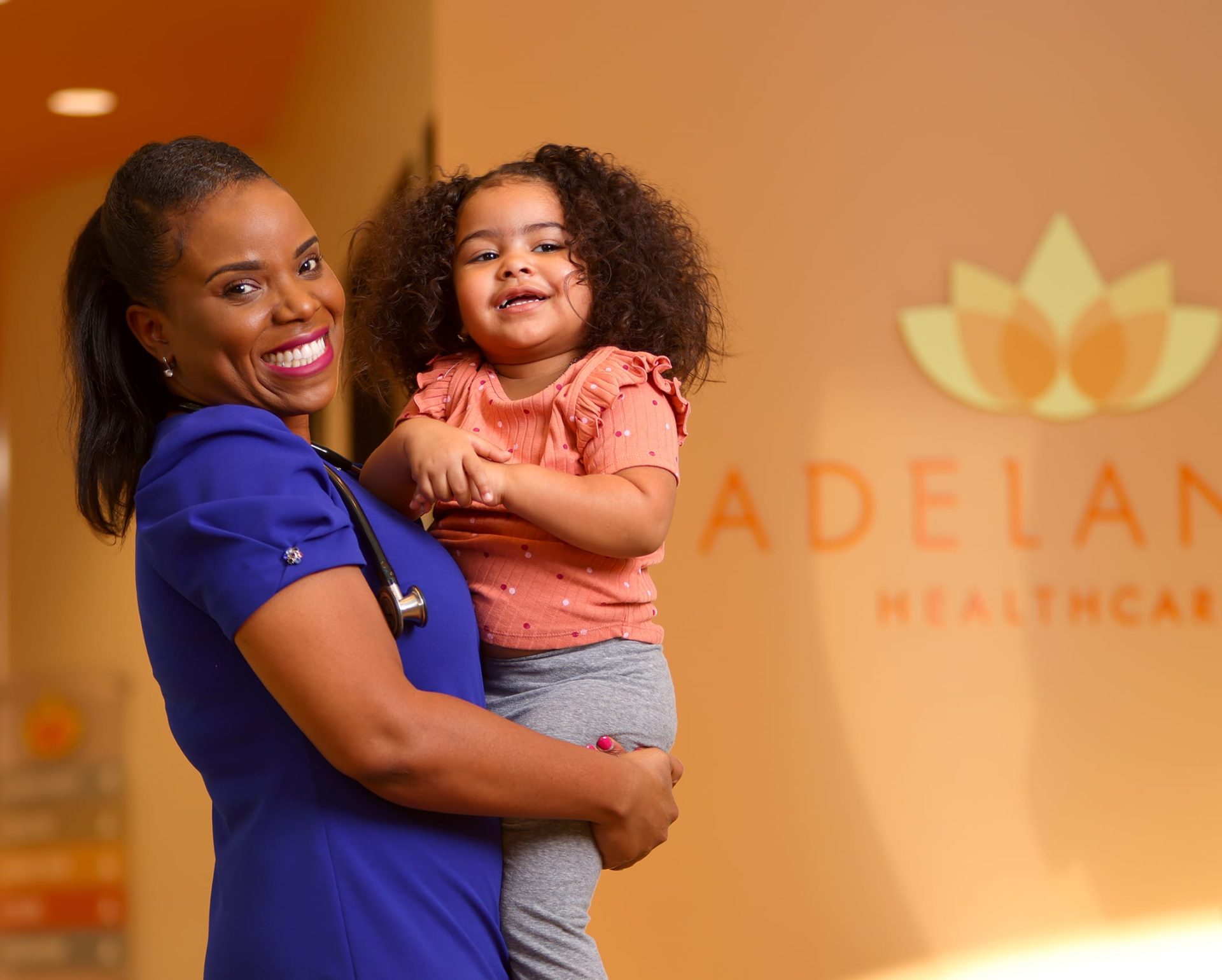 A pediatrician or family doctor posing with a patient at Adelante Healthcare in Phoenix Arizona.